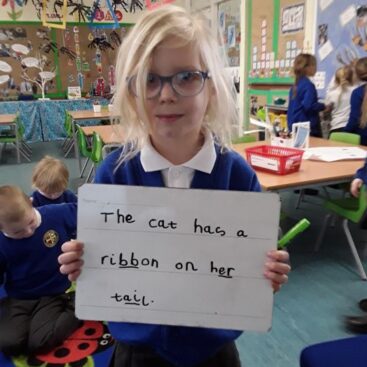 pupil in eyfs at horton kirby primary showing a whiteboard with a sentence