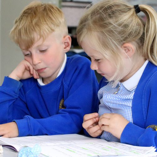 two children reading a book together in english class at horton kirby primary school