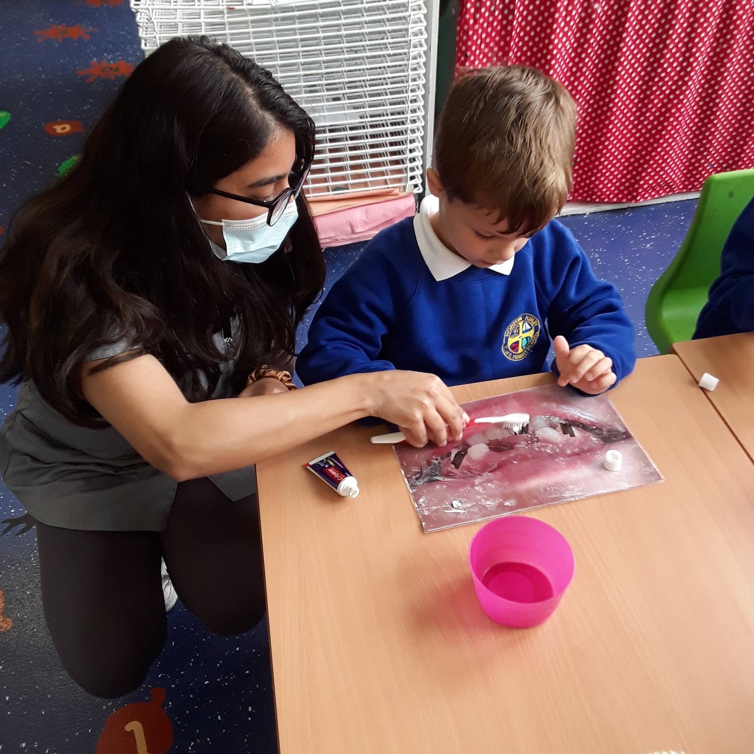 Dentist pupils learning about heroes, pupil cleaning teeth on sheet with dentist at horton kirby primary school