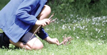 child playing with sticks in forest school at horton kirby primary school