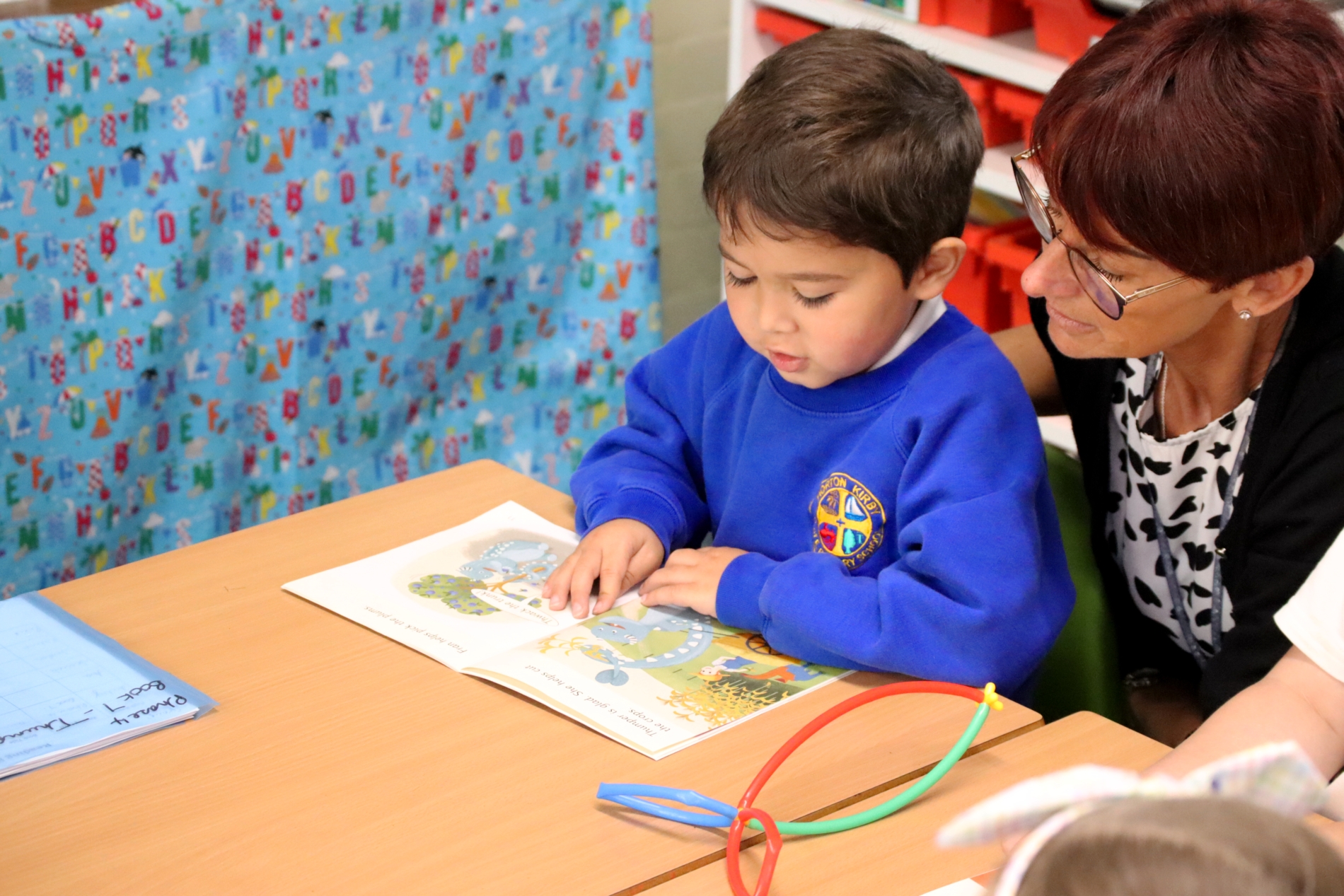 reading a book to a teacher in eyfs at horton kirby primary school