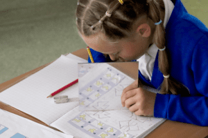 pupil using a mirror to draw identical patterns in maths lesson at horton kirby primary school