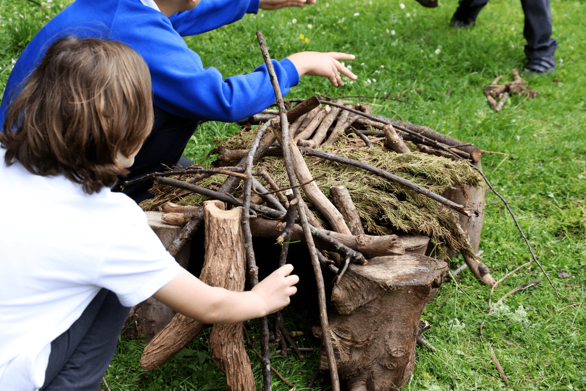 forest school pupils adding sticks to their huts in forest school at horton kirby primary school