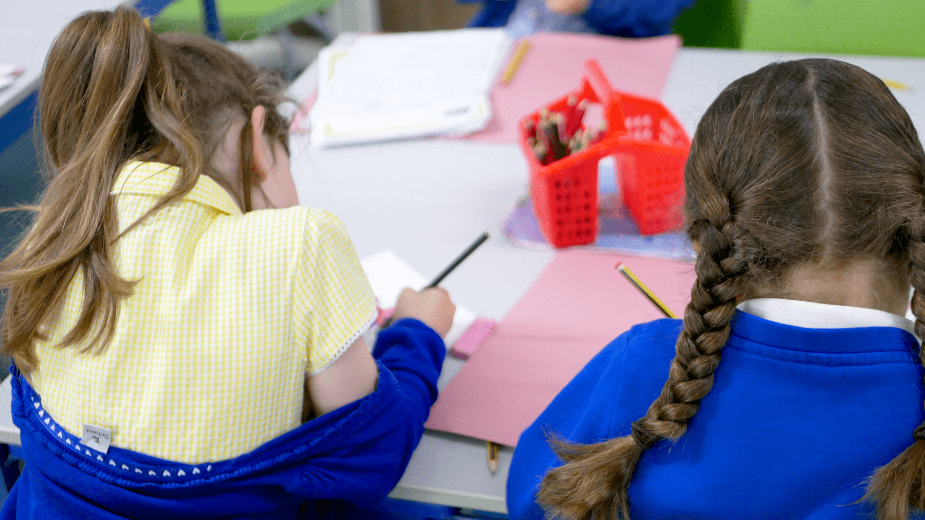 back of two pupils writing work at horton kirby primary school