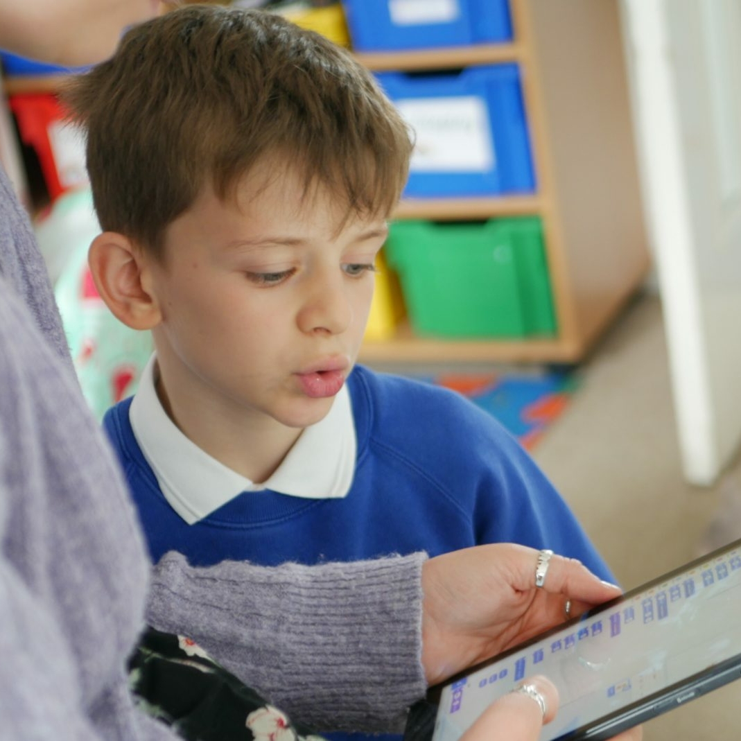 Tablet teacher pupil looking at a tablet the teacher is holding to learn about scratch, computing at horton kirby primary school