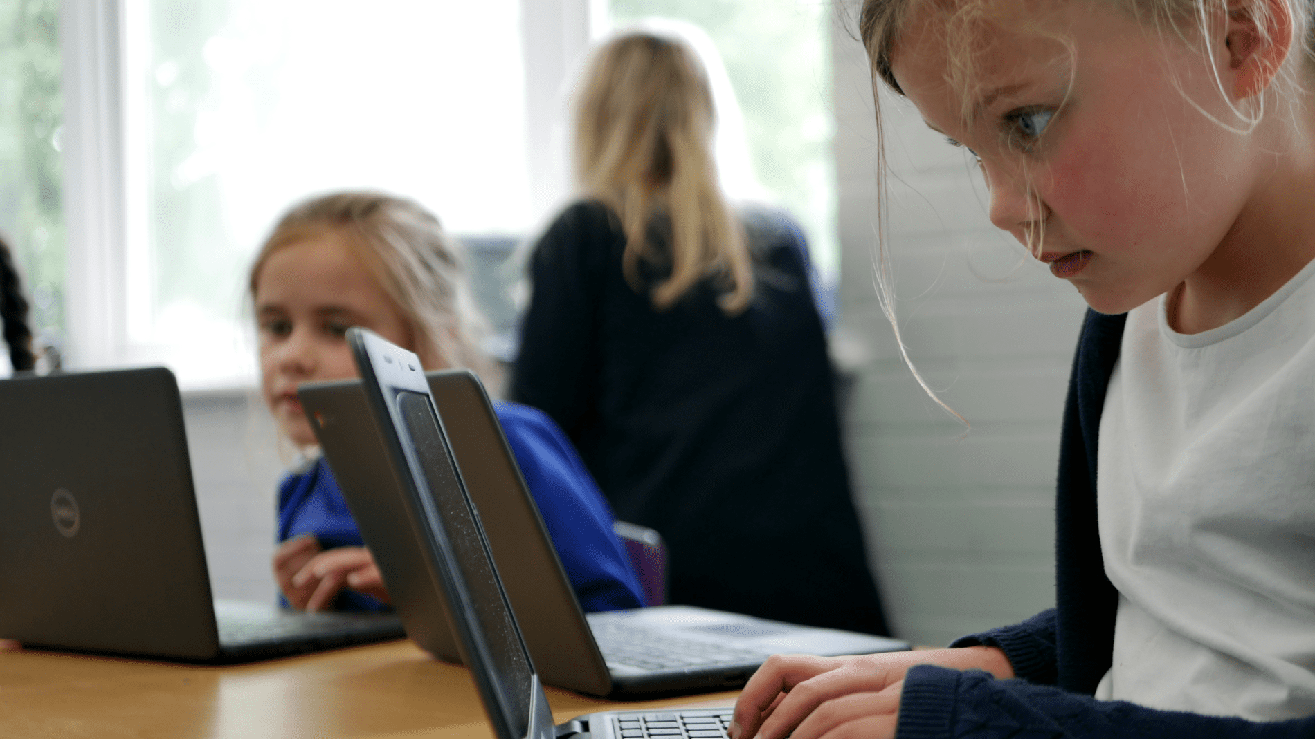 writing pupil concentrating on a laptop during computing club at horton kirby primary school