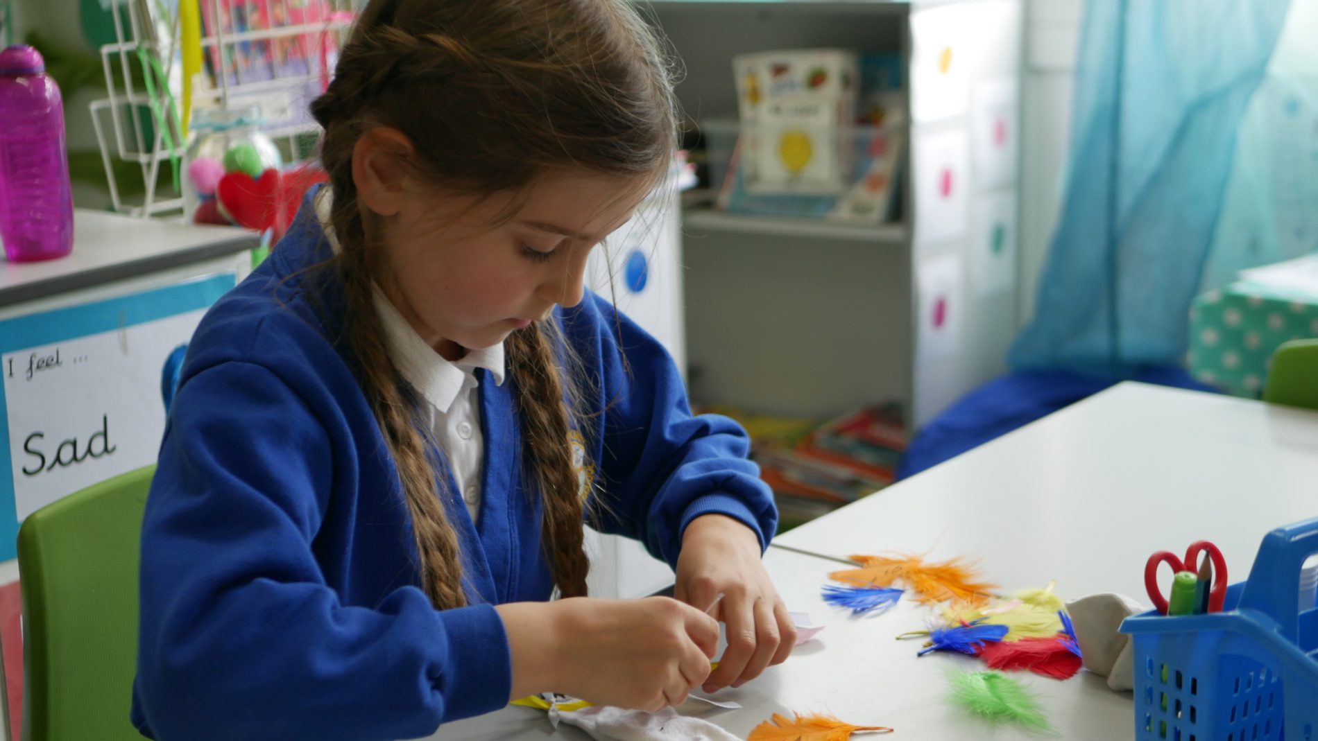 dt sock puppet girl sticking feathers to a sock puppet in a dt class at horton kirby primary school